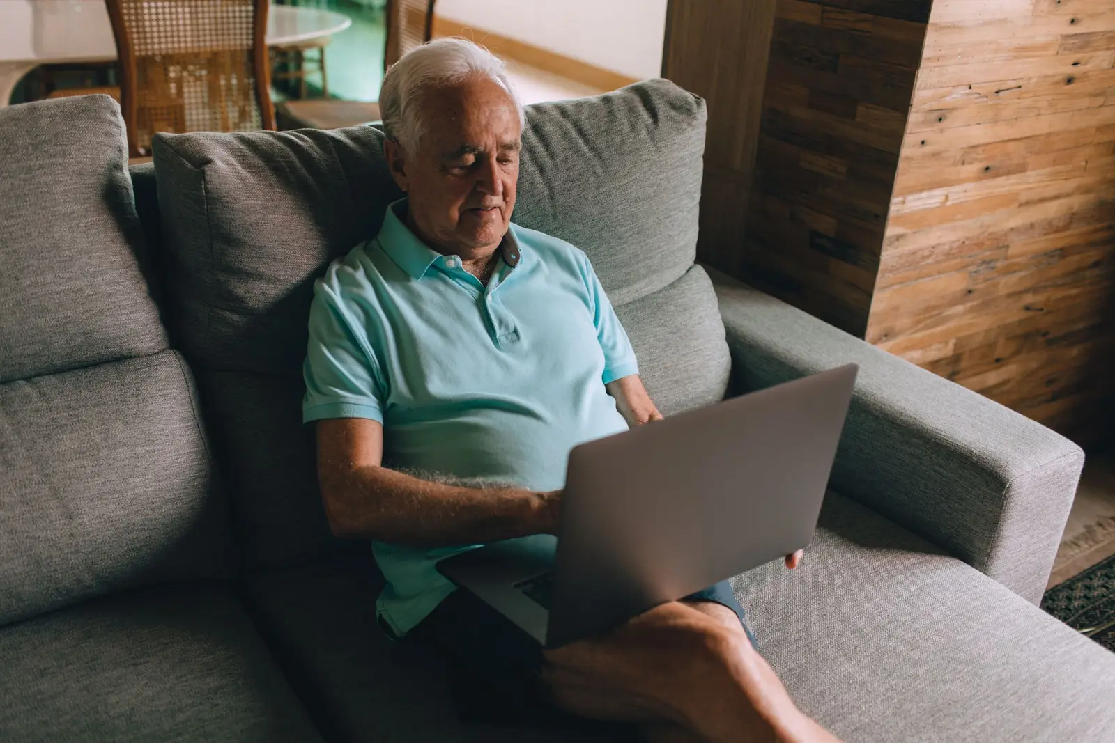 An older man using a laptop on his couch