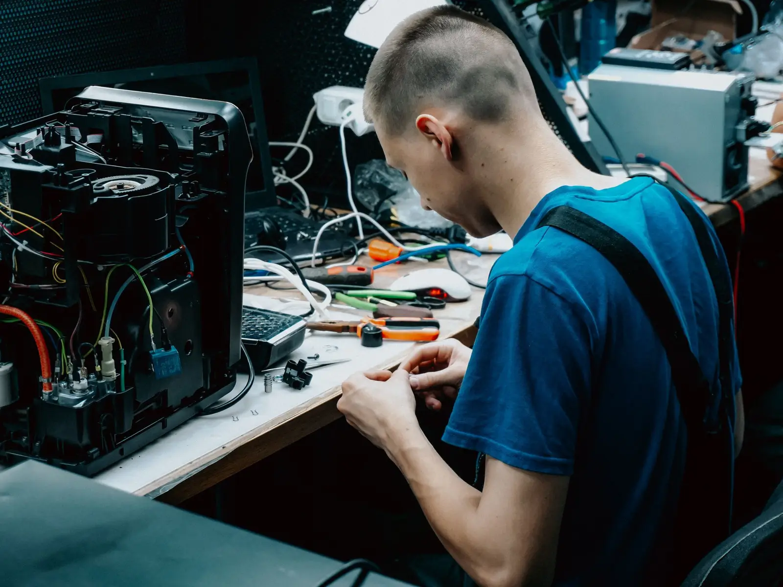A technician at a workbench with an open computer and tools